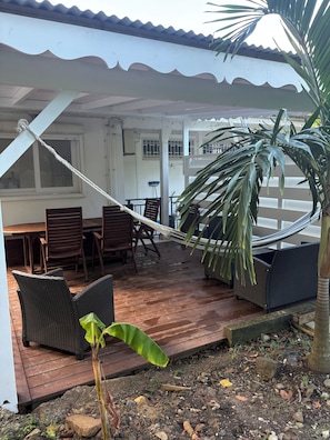 Un espacio de estar al aire libre cubierto con mobiliario de mimbre y una hamaca.