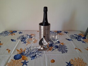 A table with a bottle of champagne, two glasses, and a small decorative bird. - L'Arèna Casa Vacanze elegante vicino al mare (Alghero)