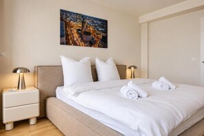 Ein Hotelzimmer mit einem Bett, zwei Nachttischen mit Lampen, einem Bild an der Wand und einer Tür.