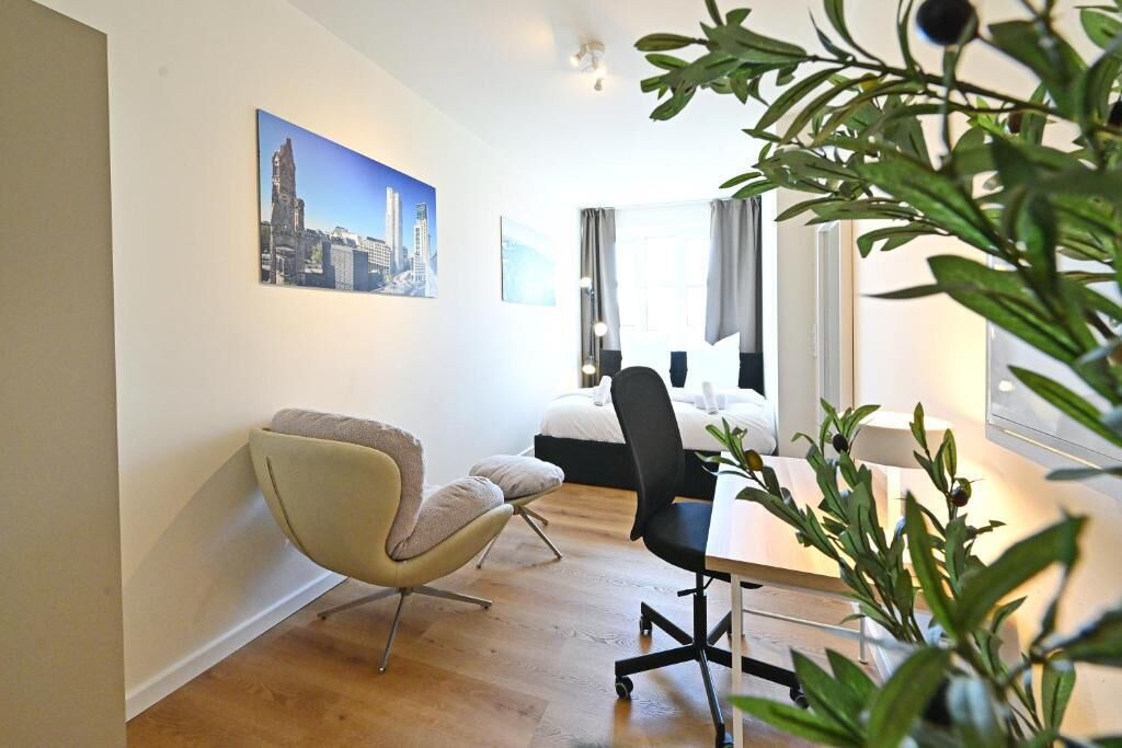 A modern hotel room with a bed, a desk, a chair, and a large window.