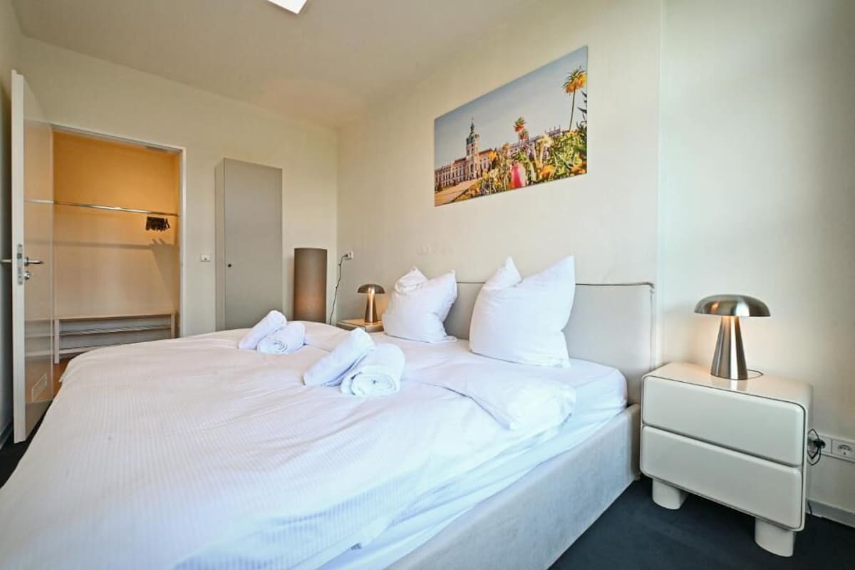 Una camera d'albergo con un letto rifatto, un quadro appeso e un armadio.