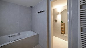 Un baño moderno con bañera, espejo y repisa.