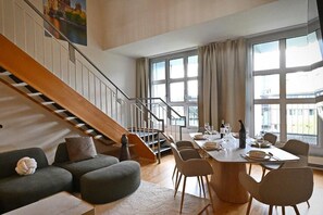Ein modernes Interieur mit einer Treppe, einem Essbereich und großen Fenstern.