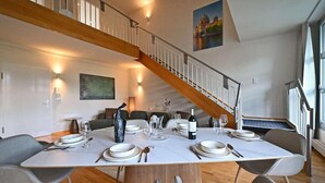 Un comedor con una escalera de madera, una mesa para cuatro personas y un cuadro en la pared.