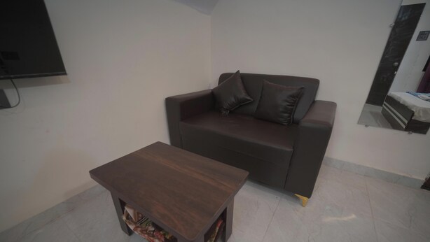 Una sala de estar con un sofá marrón oscuro, dos cojines a juego y una pequeña mesa de centro de madera.