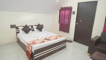Een slaapkamer met een bed, een stoel, een deur en een gordijn.