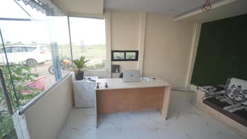 Een kamer met een bureau, een laptop, een potplant en een bank.