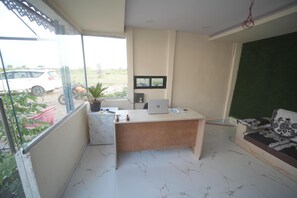 Een kamer met een bureau, een laptop, een potplant en een bank.