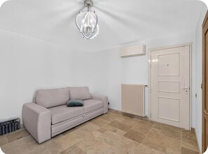 A room with a beige sofa, a radiator, a door, and a ceiling light fixture. - Luxury 5-Bedroom Villa in Cap d’Antibes with Private Pool (Antibes)