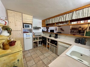 Eine kompakte Küche mit Mikrowelle, Herd und Spüle. Holzschränke und eine Arbeitsplatte mit verschiedenen Küchenutensilien.
