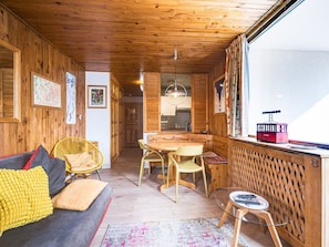 A wooden interior with a sofa, chairs, a dining table, and a window with a view. - Bright apartment village view - 6 guests (Val-d'Isère)