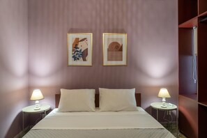 Una habitación de hotel con una cama, dos lámparas de noche y dos cuadros en la pared.