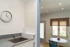 Una cocina moderna con un lavamanos y un reloj, una zona de comedor con una mesa y sillas, y un ventanal con vistas.