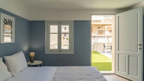 A bedroom with a bed, a window, a door, and a view of a balcony.