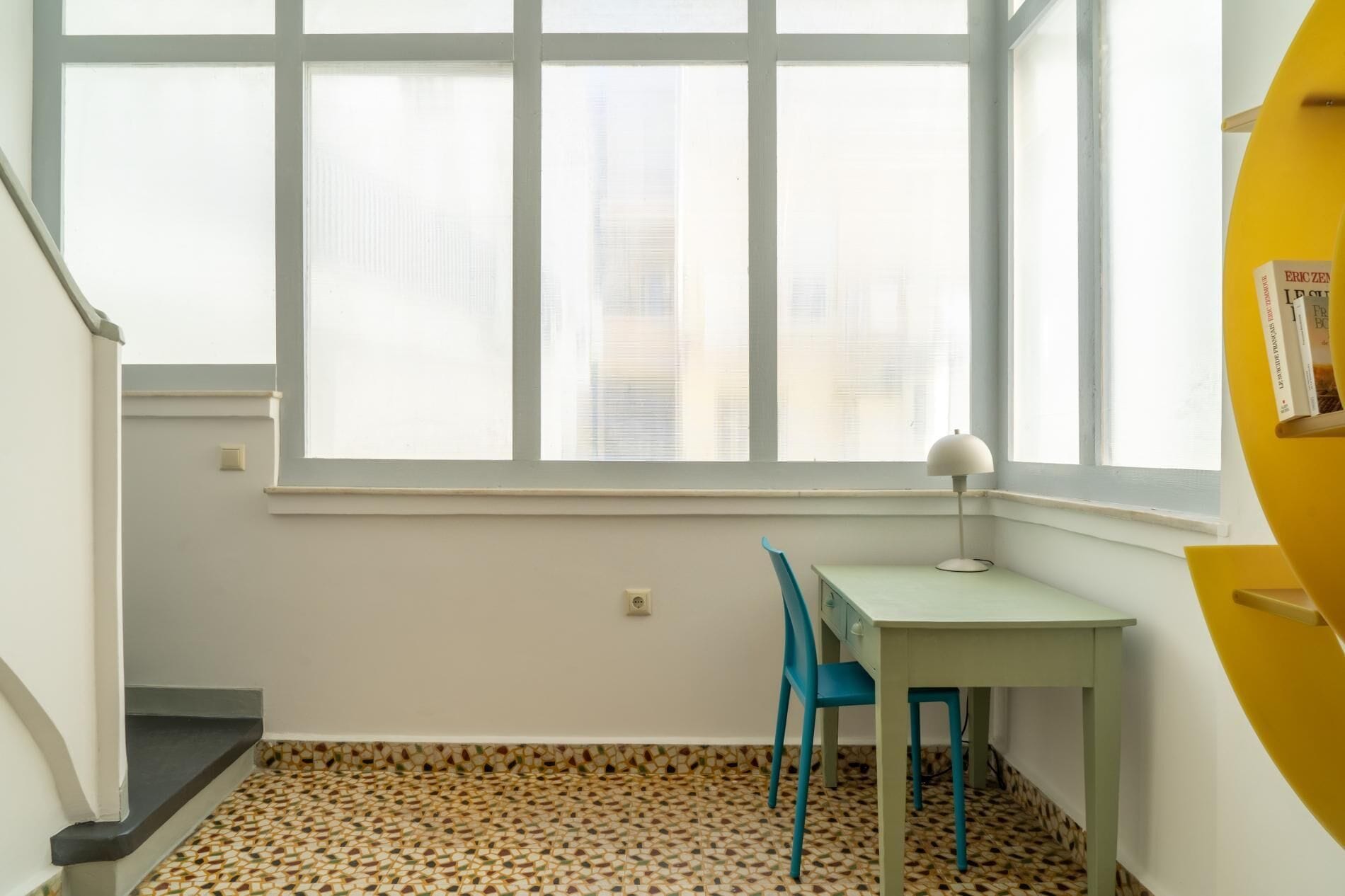 A room with a window, a desk, a chair, and a yellow cabinet.