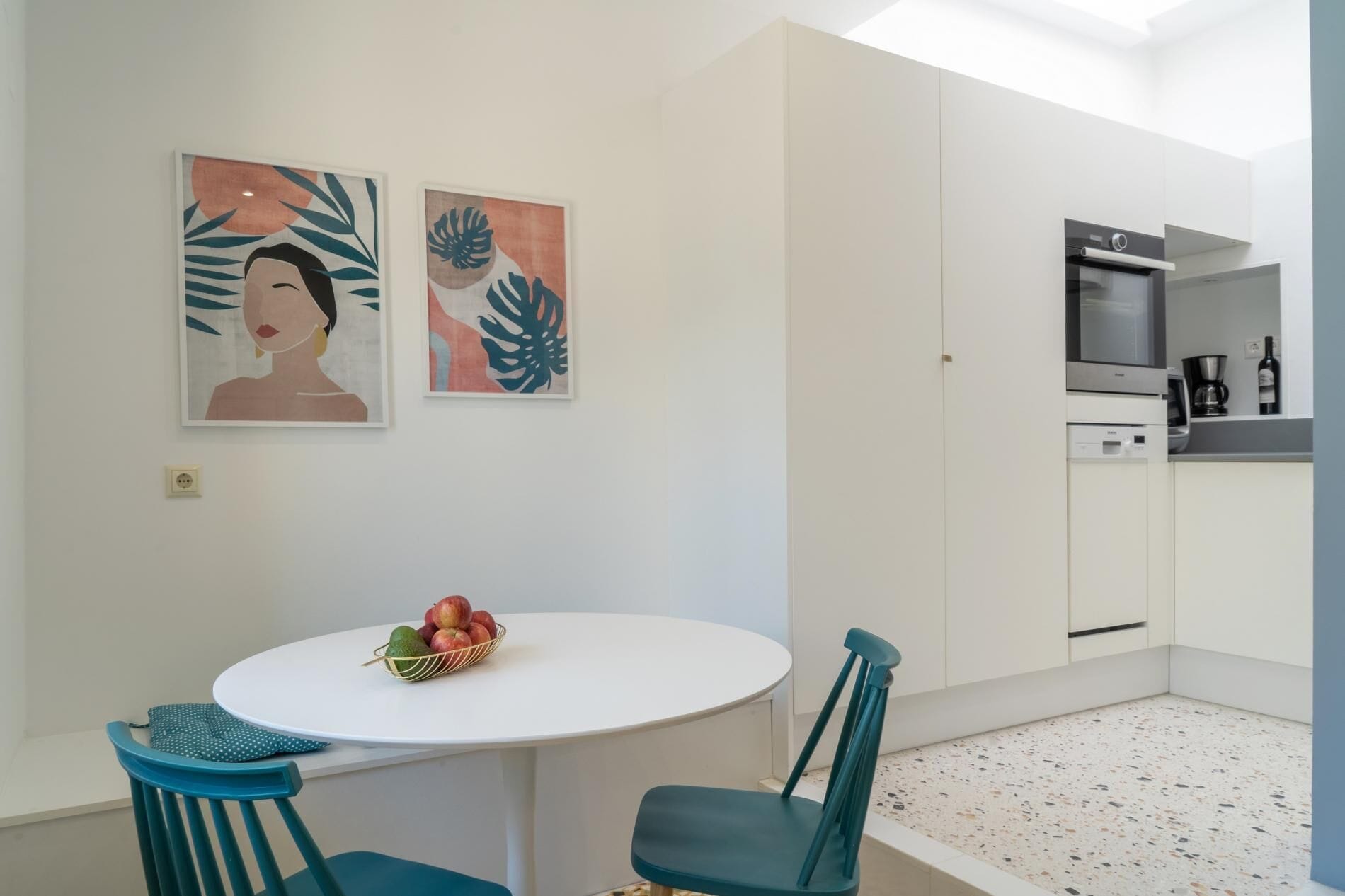 Een moderne keuken met witte kastjes, een inbouwoven en een koffieapparaat.