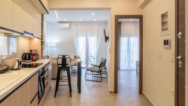 Una cocina moderna con comedor, que incluye una isla de cocina, sillas y vista al salón.