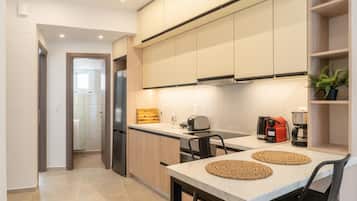 Una cocina moderna con refrigerador empotrado, cafetera y tostadora sobre la encimera.
