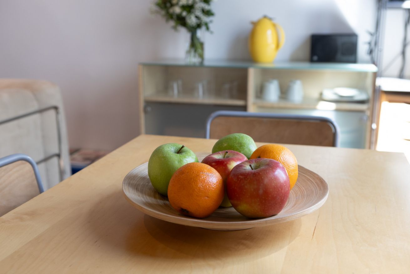Une table en bois avec une assiette de pommes et d’oranges.