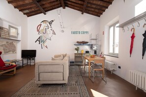 Ein Wohnzimmer mit einer Couch, einem Esstisch mit Stühlen, einem Fernseher und einer Wand mit einer Karte und einem Schild.