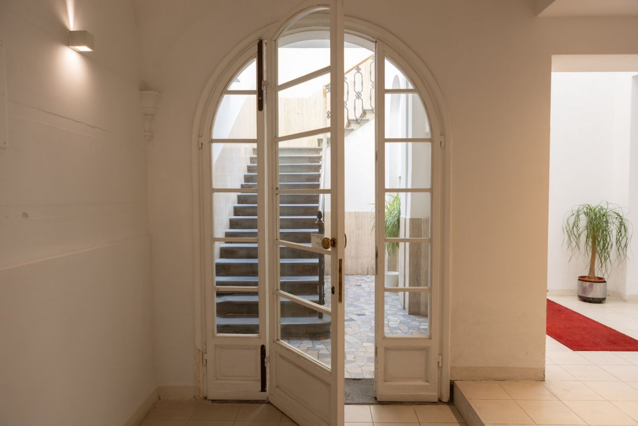 A hallway with a white arched door leading to a staircase.