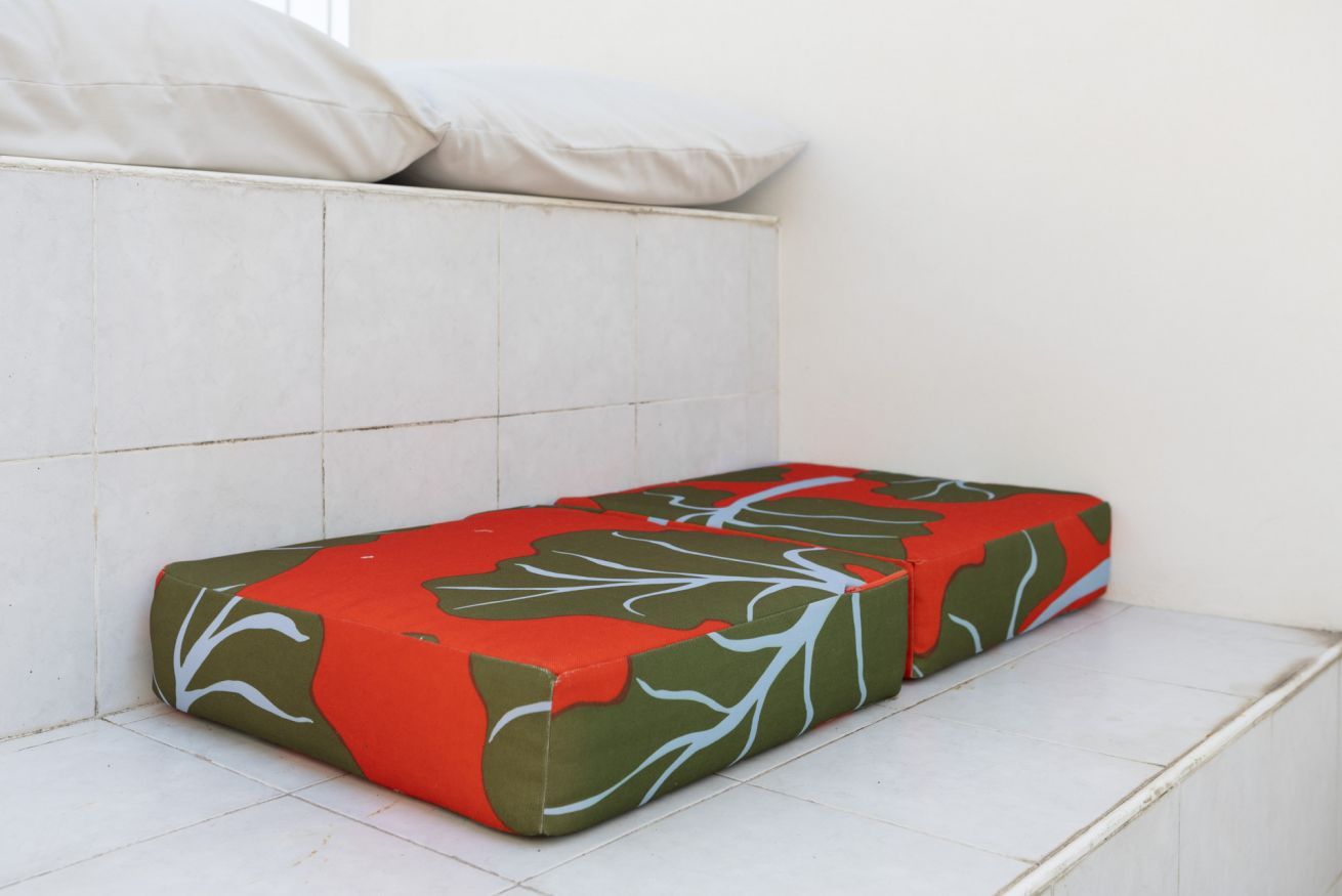 A corner bench with a patterned cushion against a white wall.