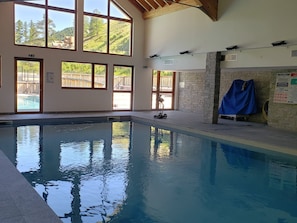 Ein Pool mit klarem Wasser, großen Fenstern und einer Steinsäule.