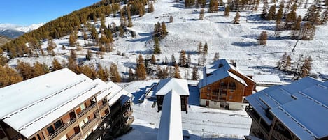 A snow-covered mountain with a wooden building featuring multiple balconies and a ski lift in the foreground.
