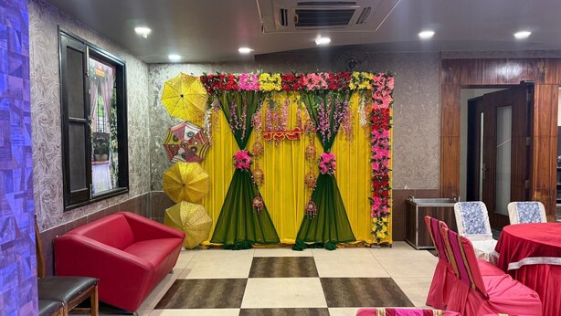 A hotel room with a checkered floor, a red sofa, and a decorative backdrop with floral arrangements.