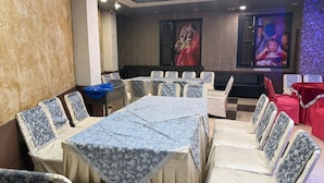 A conference room with multiple tables and chairs, a large screen, and a decorative wall.
