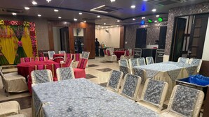 A banquet hall with tables and chairs, a stage with a microphone, and a DJ booth.