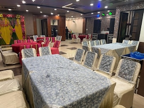 A banquet hall with tables and chairs, a stage with a microphone, and a DJ booth. - Hotel M9 (Ludhiana)