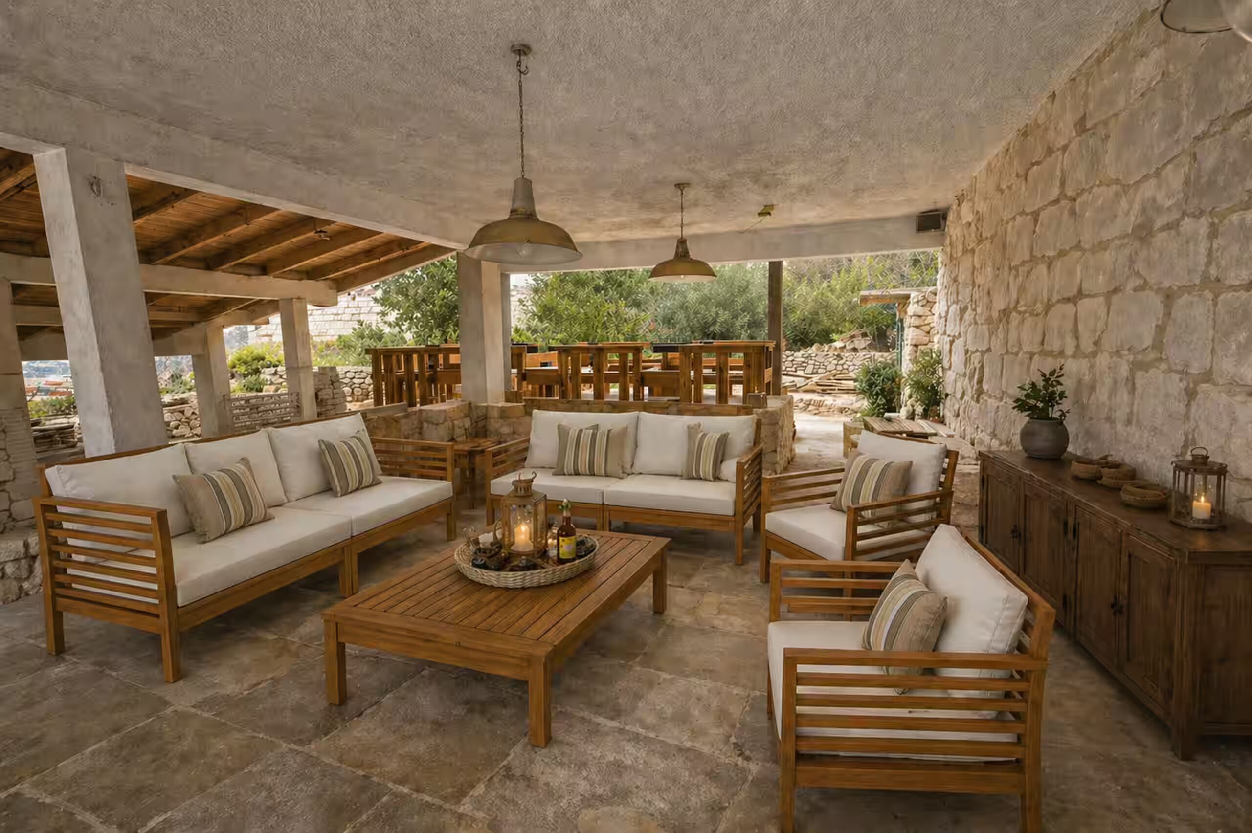 A covered outdoor seating area with wooden furniture and a stone wall.