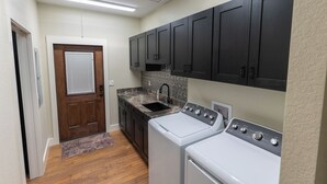 A laundry room with a washing machine, dryer, sink, and dark cabinets.