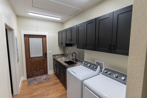 A laundry room with a washing machine, dryer, sink, and dark cabinets.