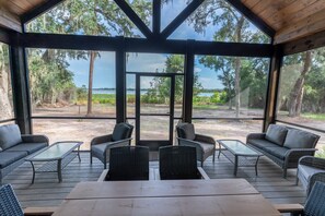 A covered outdoor seating area with wicker furniture and a view of the surrounding landscape.