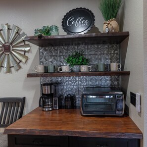 A kitchen area with a coffee bar setup, including a coffee maker, a toaster, and a sign that reads 'Coffee Bar'.