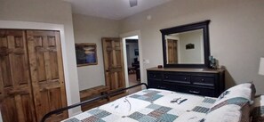 Quarto com cama, penteadeira, espelho e portas de madeira.