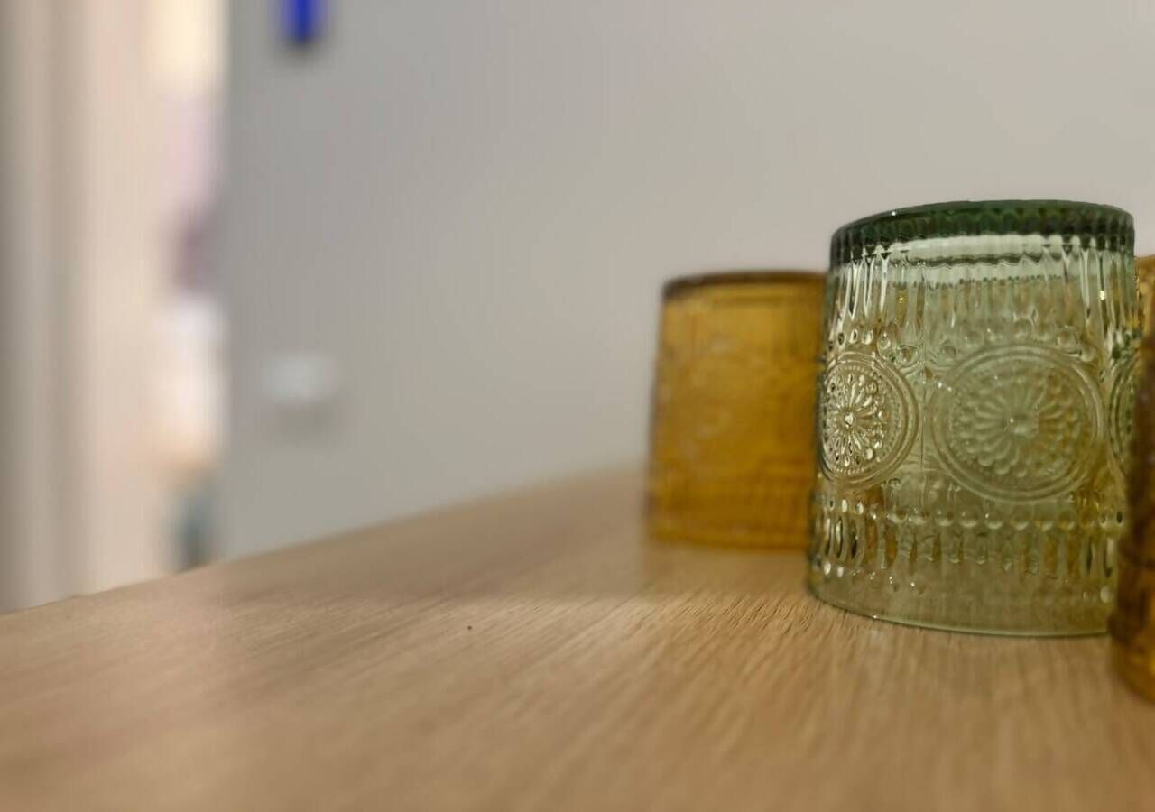 Una superficie in legno con due contenitori di vetro, uno con una texture decorativa e l'altro liscio.