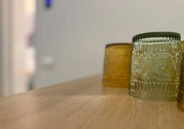 A wooden surface with two glass containers, one with a textured pattern and the other with a smooth surface.
