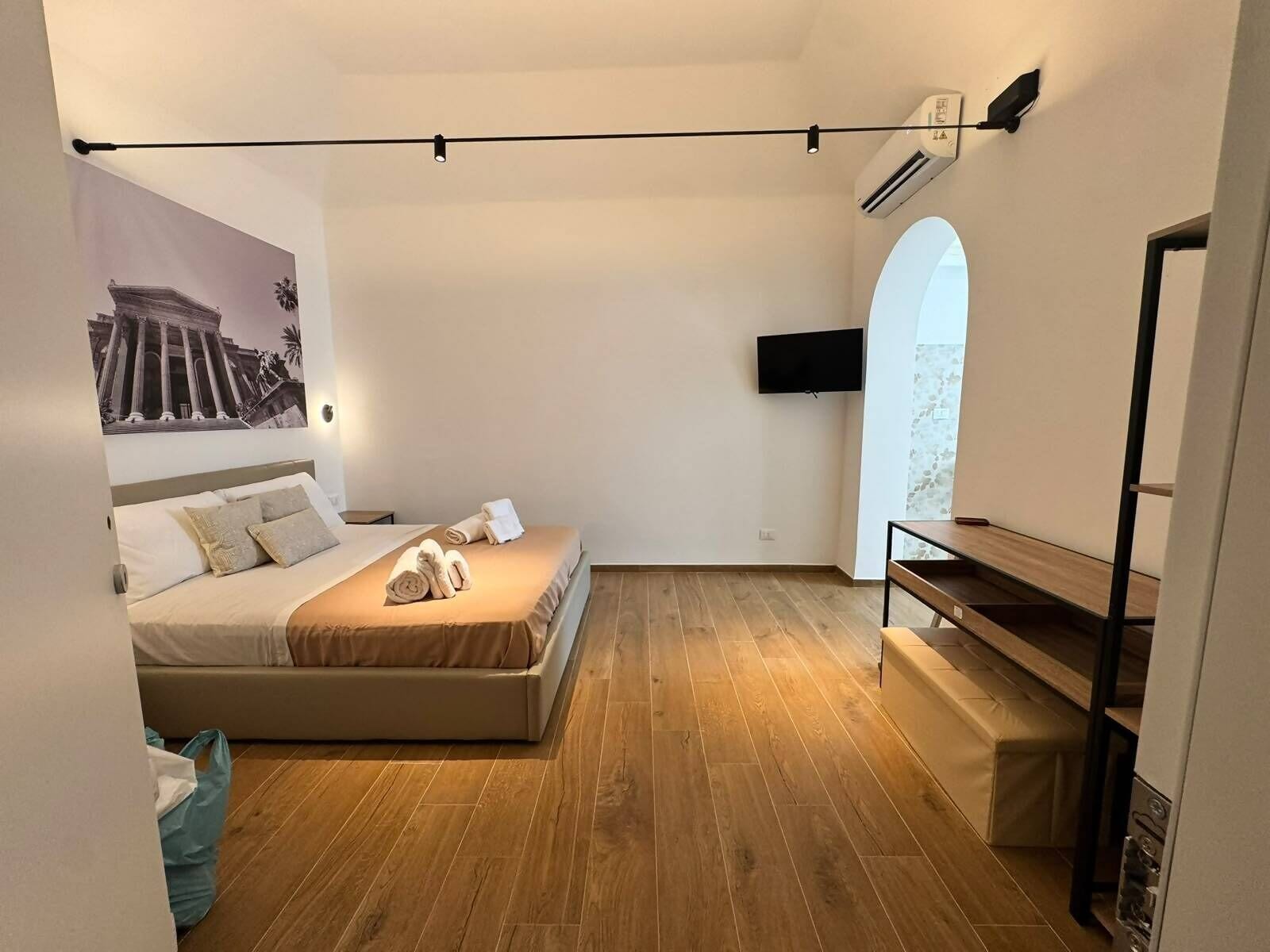 Ein modernes Schlafzimmer mit einem Bett, einem Flachbildfernseher und Holzboden.