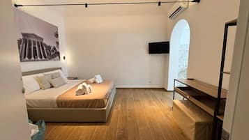 Ein modernes Schlafzimmer mit einem Bett, einem Flachbildfernseher und Holzboden.