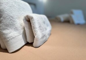 Ein weißes Handtuch auf einer strukturierten Oberfläche, vermutlich einem Bett oder Tisch.