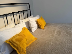 A bed with a white headboard, two white pillows, and two yellow pillows.