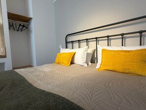 Ein Bett mit Metallgestell, zwei Kissen und einer Decke.