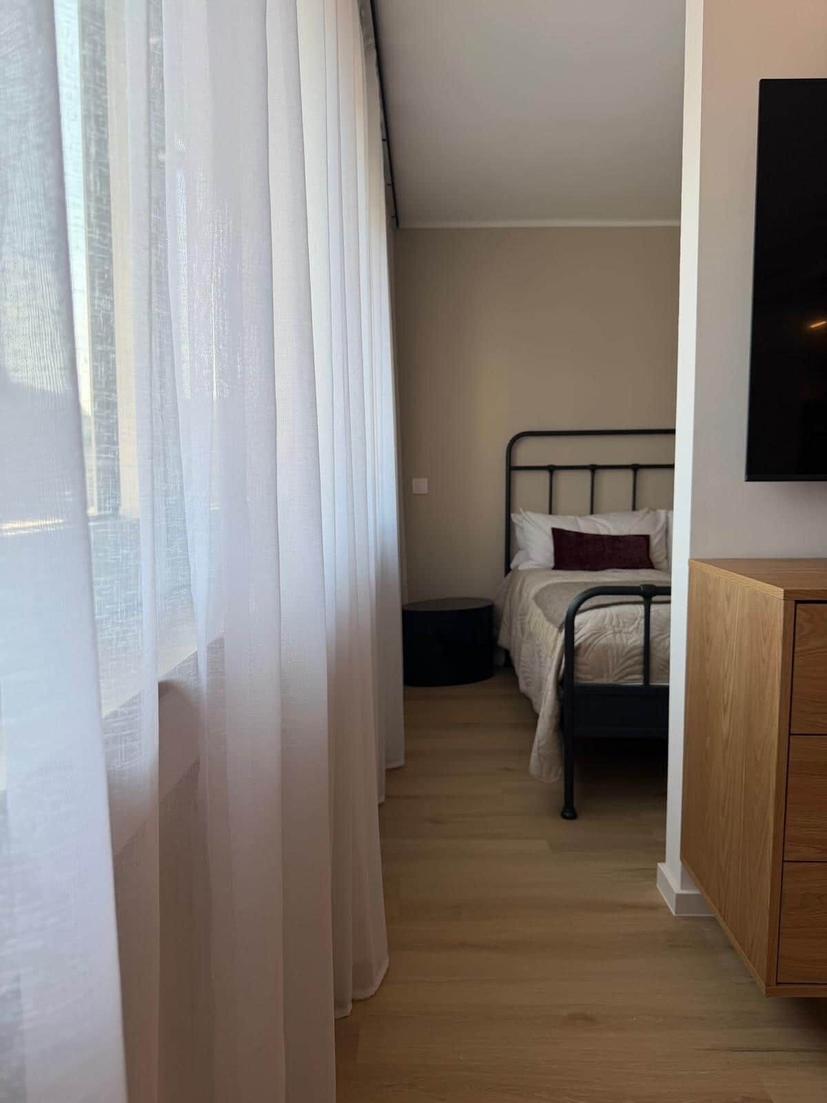 Ein Schlafzimmer mit einem Bett, einem Nachttisch und einem an der Wand montierten Fernseher.