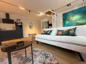 A modern living room with a sofa, a coffee table, and a painting on the wall.