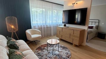 Moderni olohuone, jossa on sohva, sohvapöytä, televisio ja kaappi.