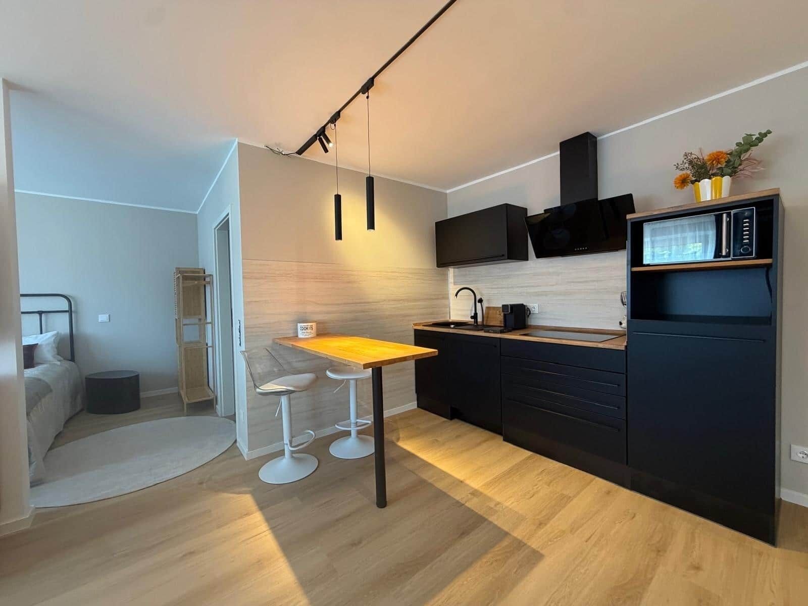 Eine moderne Küche mit einem Holztisch, Barhocker, einem eingebauten Ofen und einer Mikrowelle.