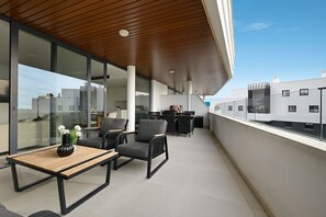 A modern outdoor seating area with a wooden table and chairs, a view of the cityscape, and a clear sky. - Modern Apartment with Terrace in Higueron (Fuengirola)